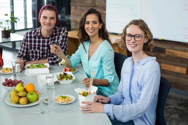 Sonriendo ejecutivos de negocios que tienen comida en la oficina