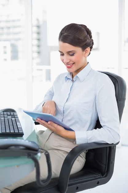 Sonriendo a la empresaria de pelo castaño con clase que usa una PC de la tableta