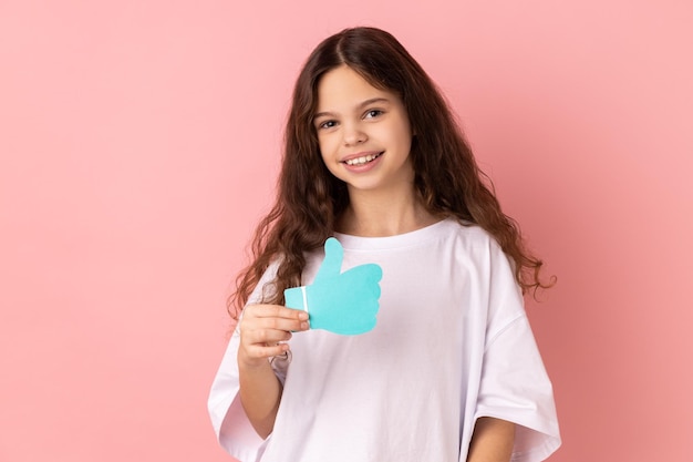 Sonriendo encantada adorable niña sosteniendo y mostrando como o pulgares arriba signo de forma de papel