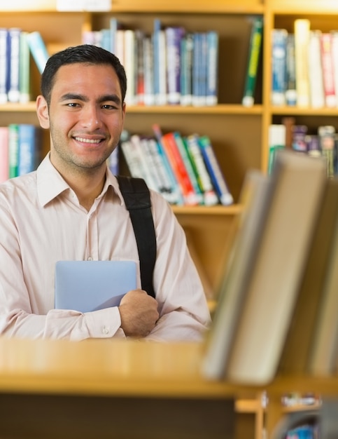 Sonriendo estudiante maduro con tablet PC en la biblioteca