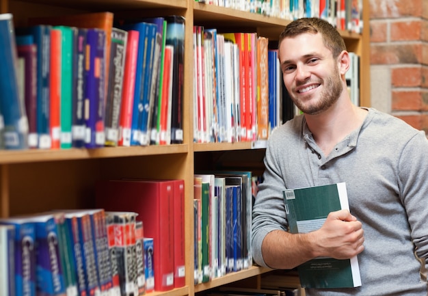 Sonriendo estudiante masculino sosteniendo un libro