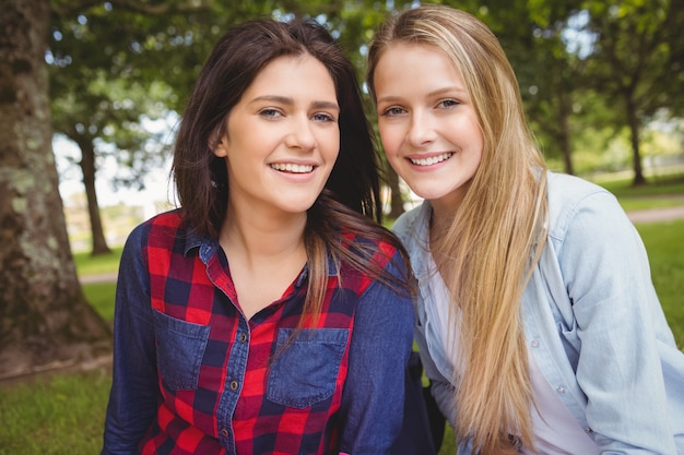 Sonriendo estudiantes mujeres posando en el parque