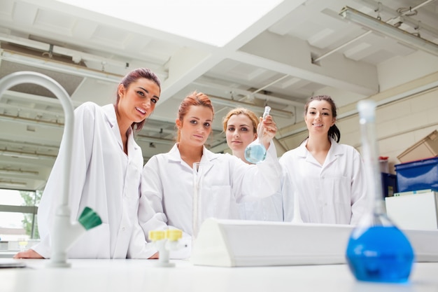 Foto sonriendo estudiantes de química sosteniendo un matraz