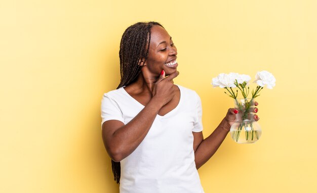 Sonriendo con una expresión feliz y confiada con la mano en la barbilla, preguntándose y mirando hacia un lado. concepto de flores decorativas