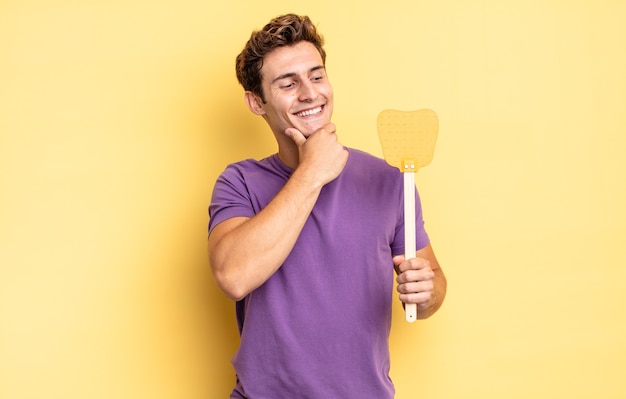 Sonriendo con una expresión feliz y confiada con la mano en la barbilla, preguntándose y mirando hacia un lado. concepto de matar moscas