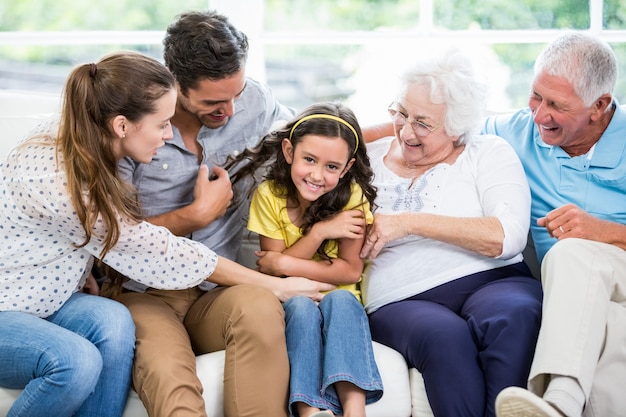 Sonriendo familia multigeneración sentado en el sofá