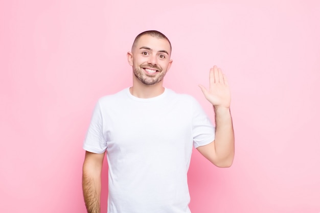 sonriendo feliz y alegremente, saludando con la mano, dándote la bienvenida y saludándote, o diciéndote adiós