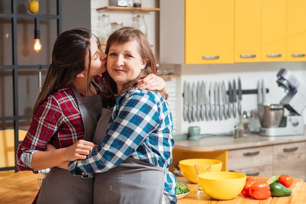 Sonriendo feliz familia madre e hija en la cocina