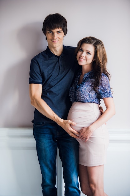 Sonriendo feliz pareja esperando a un niño se inclina el uno al otro en casa