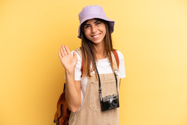 Sonriendo felizmente agitando la mano dándote la bienvenida y saludándote