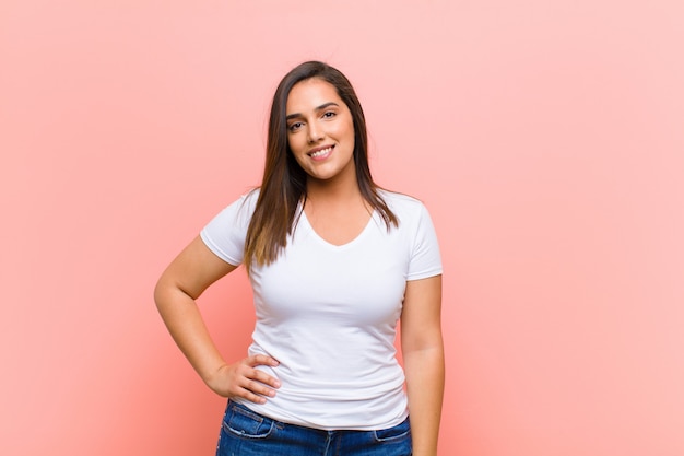 sonriendo felizmente con una mano en la cadera y una actitud segura, positiva, orgullosa y amigable