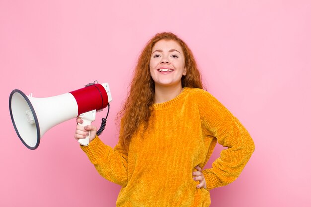 sonriendo felizmente con una mano en la cadera y una actitud segura, positiva, orgullosa y amigable