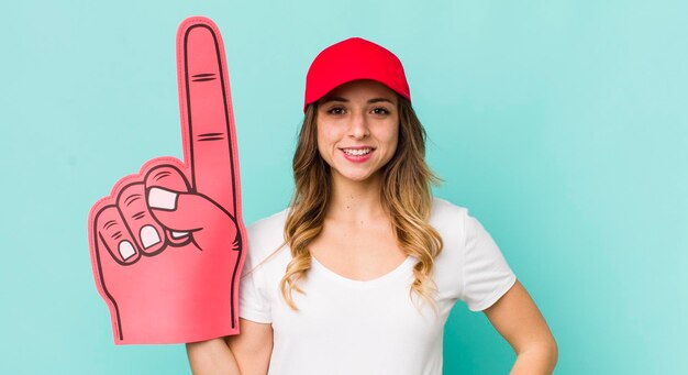 Foto sonriendo felizmente con una mano en la cadera y confiado