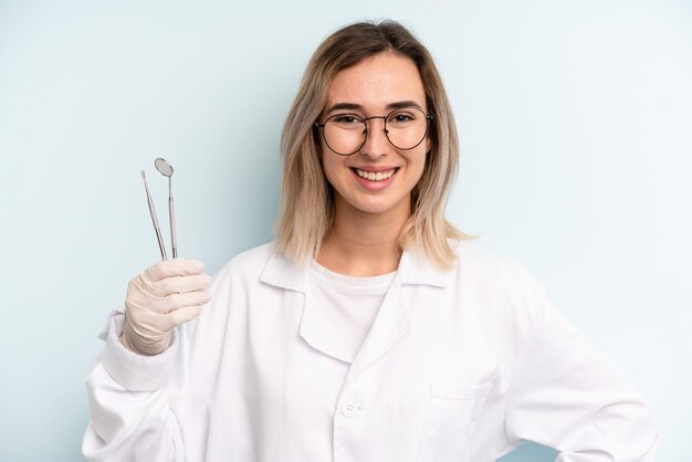 sonriendo felizmente con una mano en la cadera y confiado