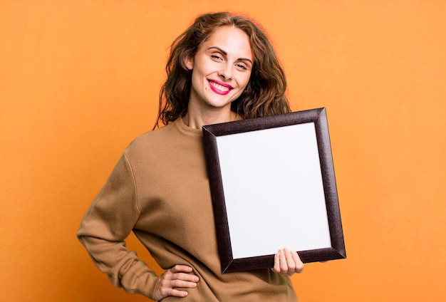 sonriendo felizmente con una mano en la cadera y confiado