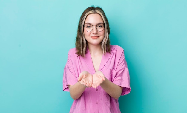 Sonriendo felizmente con una mirada amistosa, segura y positiva, ofreciendo y mostrando un objeto o concepto.