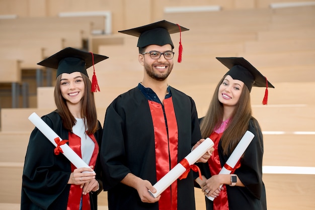 Sonriendo graduados manteniendo diplomas.