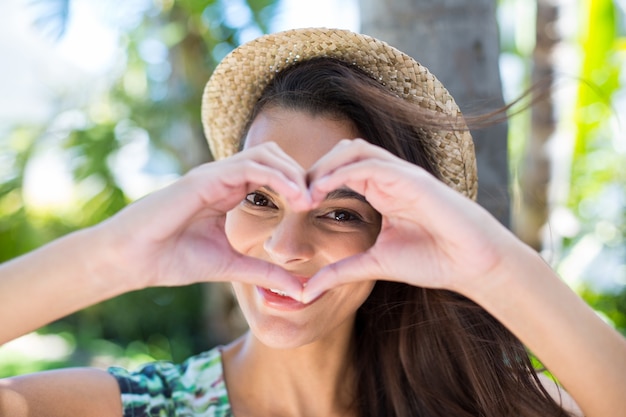 Sonriendo hermosa morena haciendo forma de corazón con sus manos