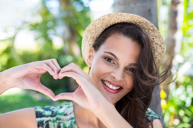 Sonriendo hermosa morena haciendo forma de corazón con sus manos