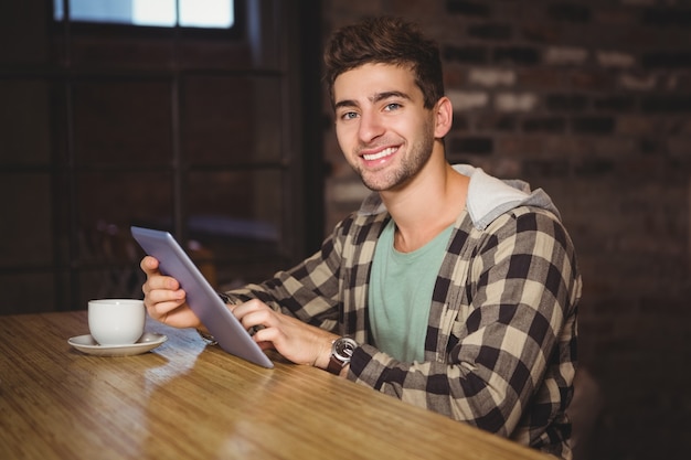 Sonriendo hipster sentado y usando la tableta