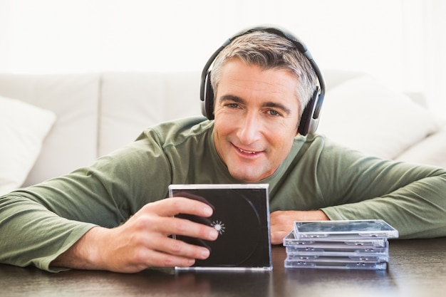 Sonriendo el hombre escuchando música y sosteniendo cd