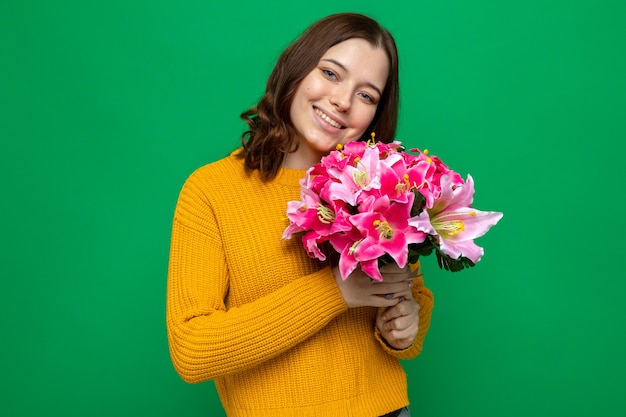 Sonriendo inclinando la cabeza hermosa joven sosteniendo bouquet