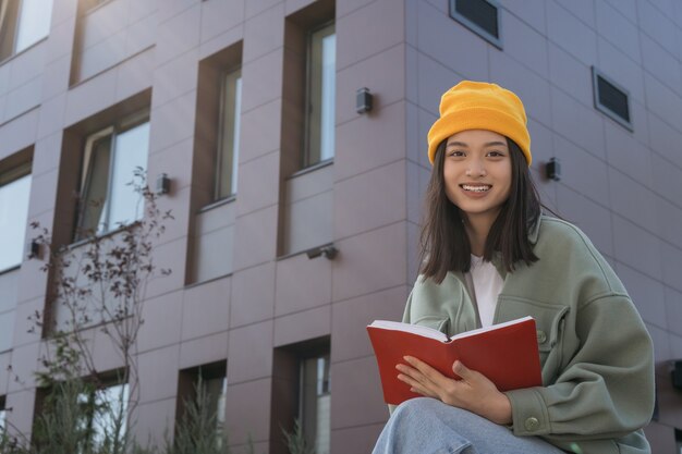 Sonriendo libro de lectura de estudiantes asiáticos mirando a la cámara Concepto de educación