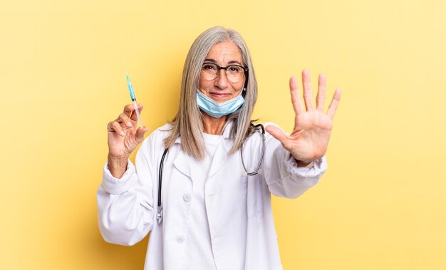 Sonriendo y luciendo amigable, mostrando el número cinco o quinto con la mano hacia adelante, contando hacia atrás. concepto médico y vacuna