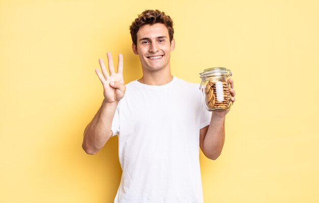 Sonriendo y luciendo amigable, mostrando el número cuatro o cuarto con la mano hacia adelante, contando hacia atrás. concepto de galletas caseras