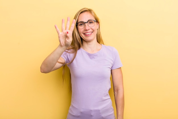 Sonriendo y luciendo amigable mostrando el número cuatro o cuarto con la mano hacia adelante contando hacia atrás