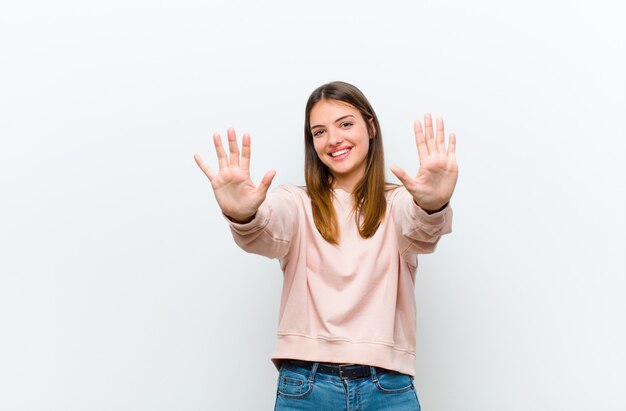 sonriendo y luciendo amigable, mostrando el número diez o décimo con la mano hacia adelante, contando hacia atrás