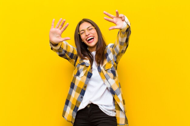 sonriendo y luciendo amigable, mostrando el número nueve o noveno con la mano hacia adelante, contando hacia atrás