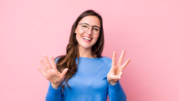 Sonriendo y luciendo amigable mostrando el número ocho u octavo con la mano hacia adelante contando hacia atrás