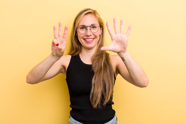 Sonriendo y luciendo amigable mostrando el número ocho u octavo con la mano hacia adelante contando hacia atrás