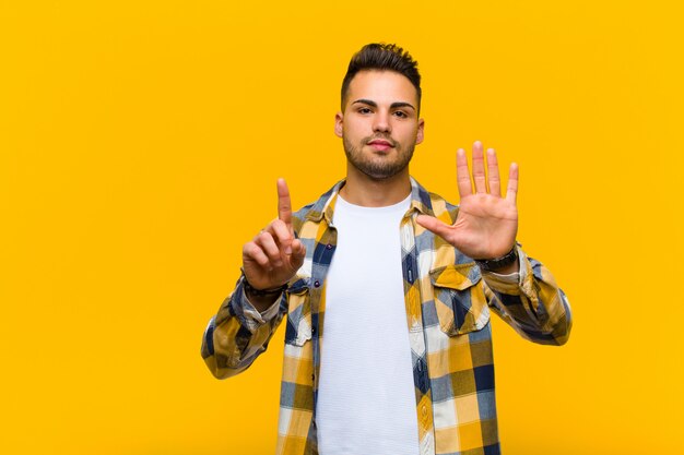 sonriendo y luciendo amigable, mostrando el número seis o sexto con la mano hacia adelante, contando hacia atrás