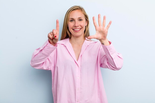 Sonriendo y luciendo amigable mostrando el número seis o sexto con la mano hacia adelante contando hacia atrás