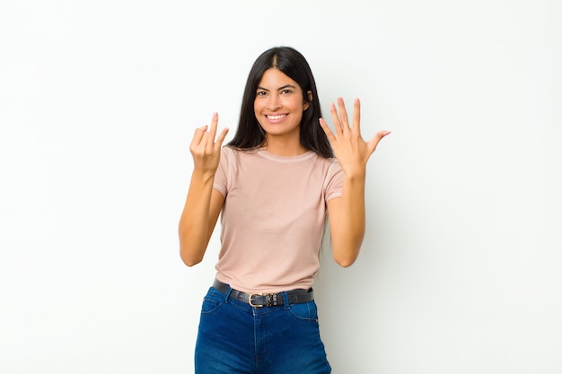 sonriendo y luciendo amigable, mostrando el número siete o séptimo con la mano hacia adelante, contando hacia atrás