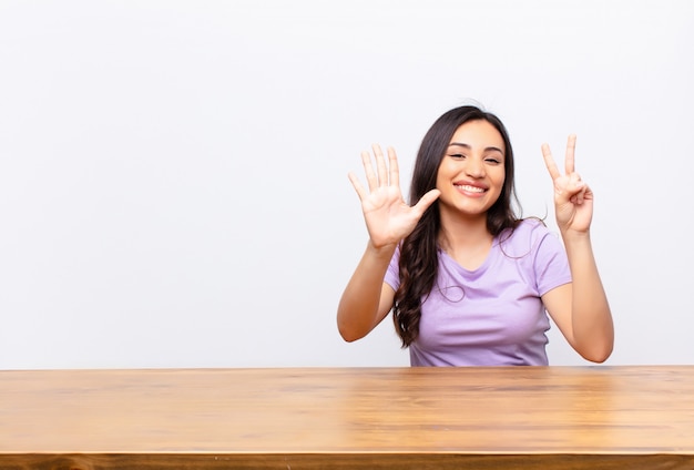 sonriendo y luciendo amigable, mostrando el número siete o séptimo con la mano hacia adelante, contando hacia atrás