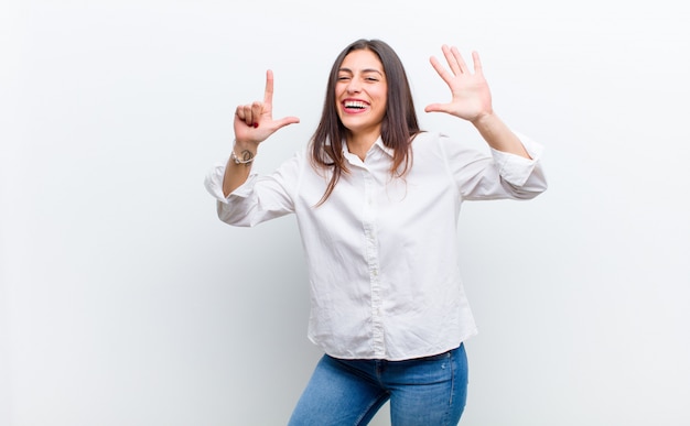 sonriendo y luciendo amigable, mostrando el número siete o séptimo con la mano hacia adelante, contando hacia atrás