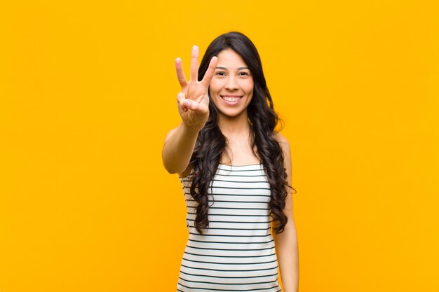 sonriendo y luciendo amigable, mostrando el número tres o tercero con la mano hacia adelante, contando hacia atrás