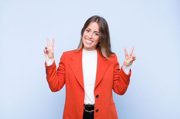 sonriendo y luciendo feliz, amigable y satisfecho, gesticulando victoria o paz con ambas manos