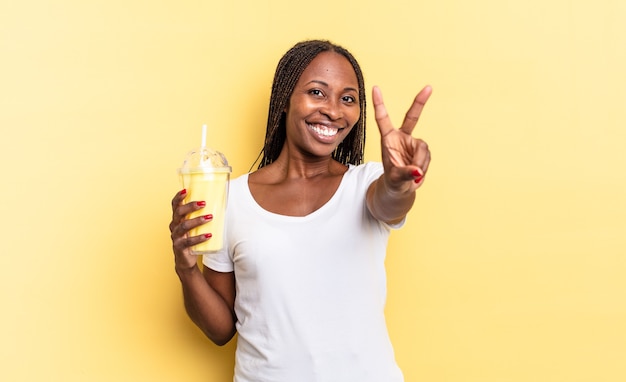 Sonriendo y luciendo feliz, despreocupado y positivo, gesticulando victoria o paz con una mano. concepto de batido