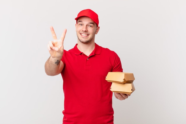 sonriendo y luciendo feliz, despreocupado y positivo, gesticulando victoria o paz con una mano