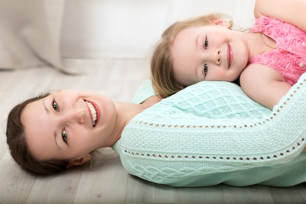 Sonriendo madre e hija en el piso