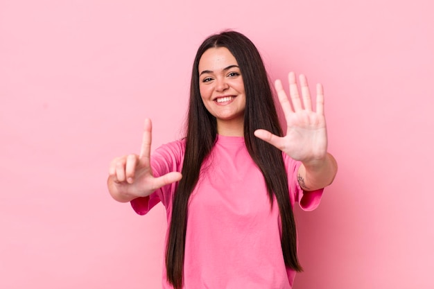 Foto sonriendo y mirando amigable mostrando el número siete o séptimo con la mano hacia atrás