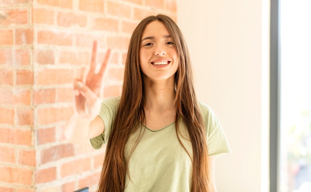 sonriendo y mirando amistosamente, mostrando el número dos o el segundo con la mano hacia adelante, contando hacia atrás