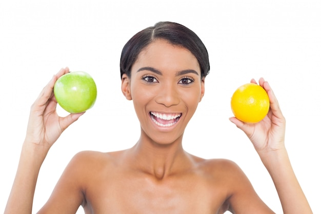 Sonriendo modelo atractivo con frutas en ambas manos