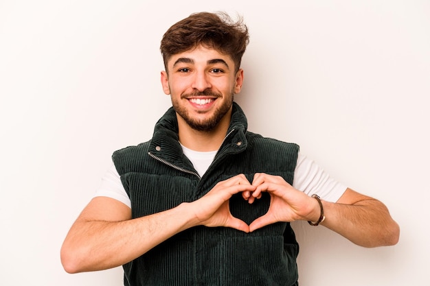 Sonriendo y mostrando una forma de corazón con las manos.