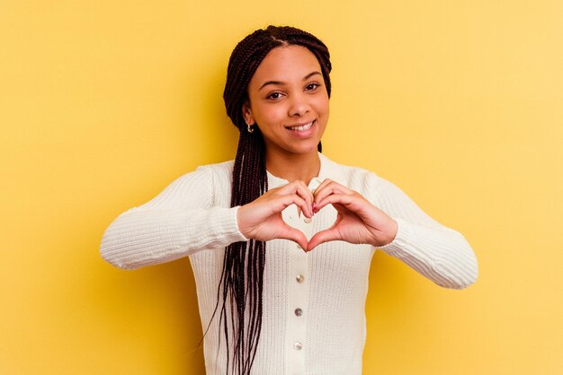 Sonriendo y mostrando una forma de corazón con las manos.