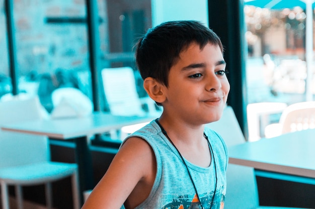 Sonriendo de niño mirando hacia otro lado mientras está sentado en la mesa en el restaurante